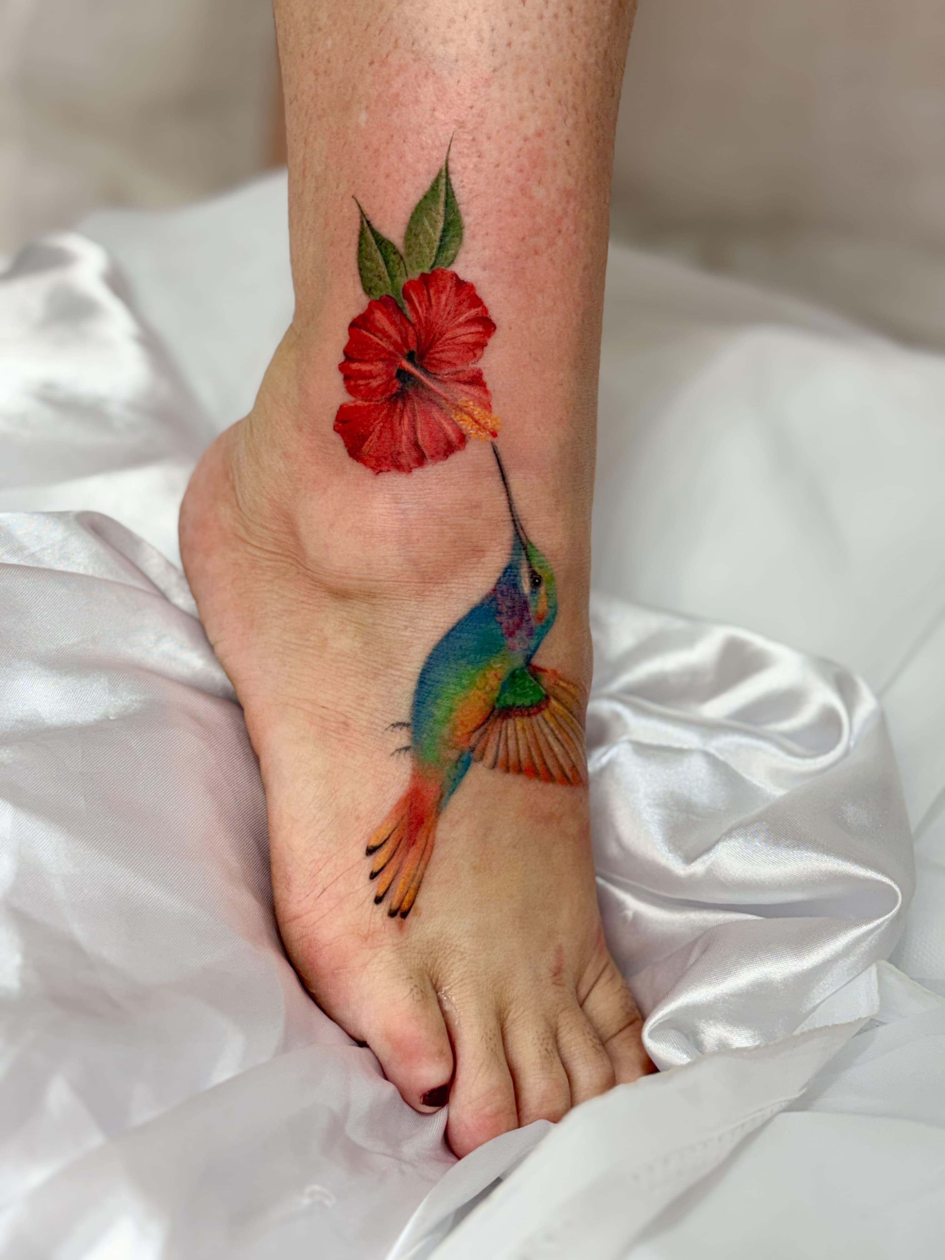 Tatuagem colorida de beija-flor e hibisco vermelho